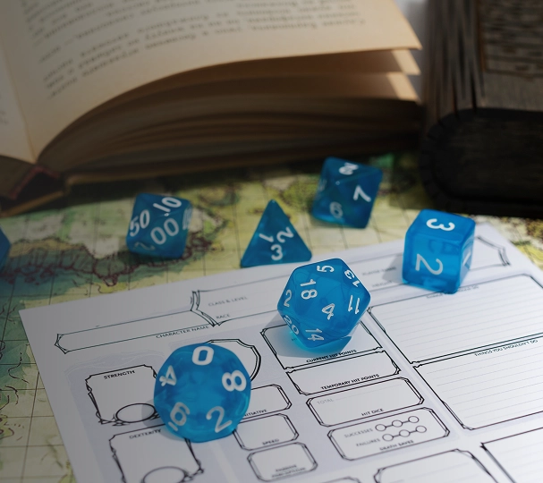Blauwe dobbelstenen op een rollenspel karakterblad met kaart en boek op tafel